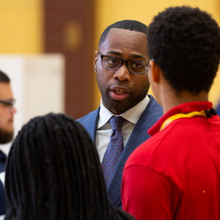a person in a suit talking to a group of people