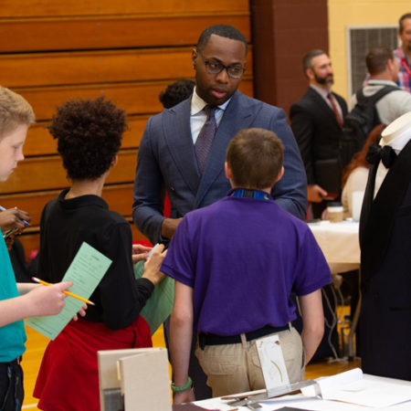 a person in a suit standing in front of a group of people