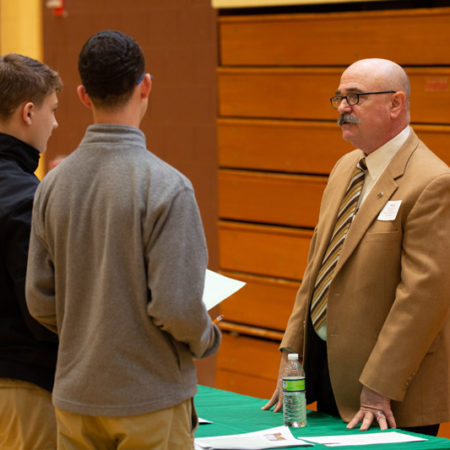 a person talking to a group of young men