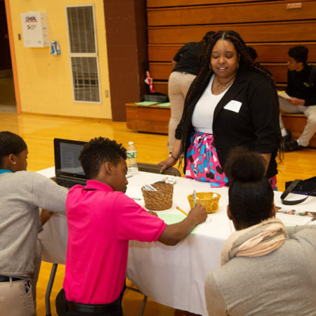 a person standing behind a table with people around it