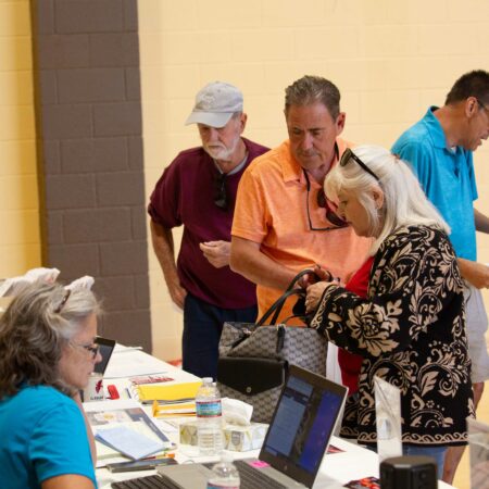 a group of people standing around a table with laptops