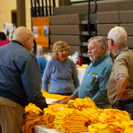 a group of people standing around a table with yellow cloths
