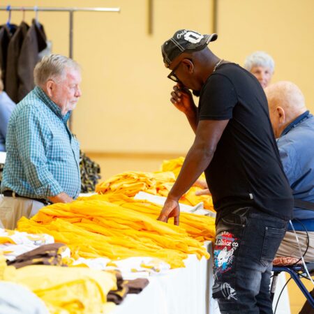 a person standing in front of a table with yellow shirts