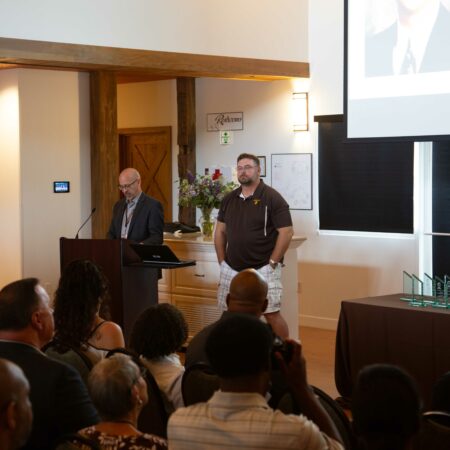 a person standing at a podium with a person in front of a crowd
