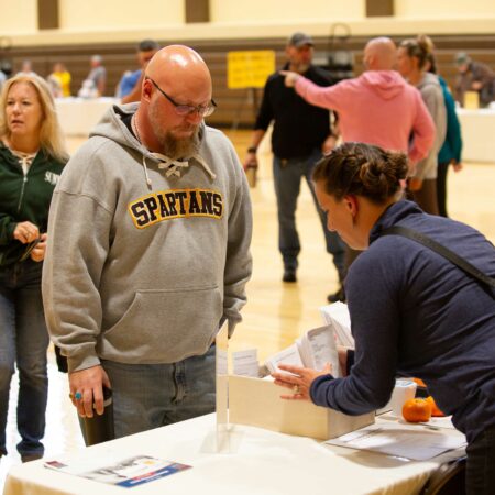 a person standing at a table with a person in the background