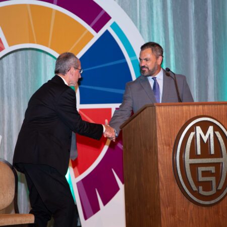a person shaking hands with another person at a podium