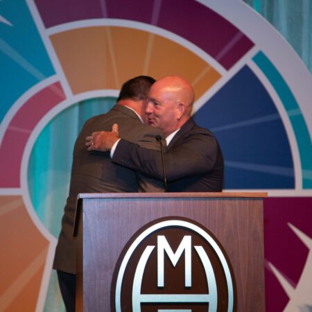 a couple of men hugging at a podium
