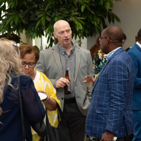 a person in a grey suit talking to a group of people
