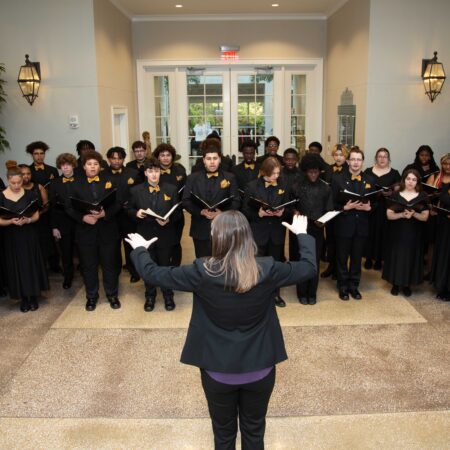 a person standing in front of a group of people singing