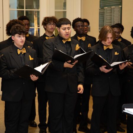 a group of people in black suits singing