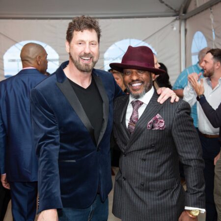 a person in a suit and tie with another person in a hat