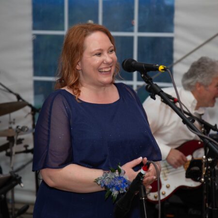 a person in a blue dress with a microphone in front of a person playing guitar