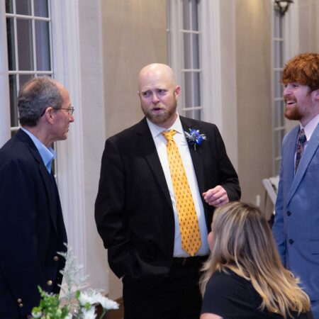 a person in a suit and tie standing in a room with people
