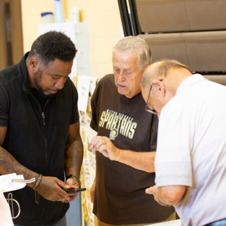 a group of men looking at a cellphone