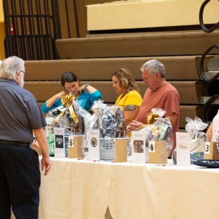 a group of people sitting at a table with a table with items