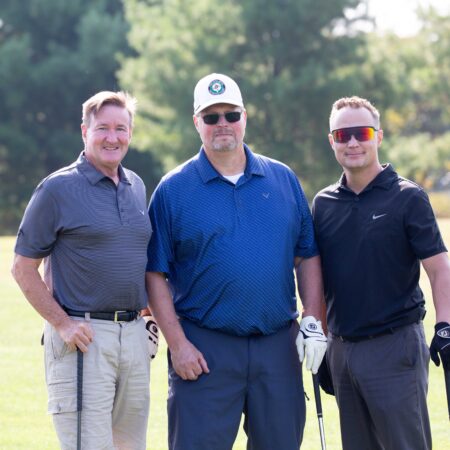 a group of men standing on a golf course