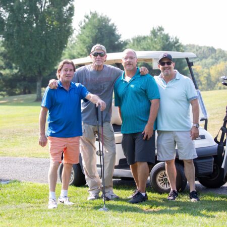 a group of men standing in front of a golf cart
