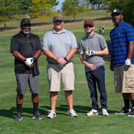 a group of men standing on a golf course