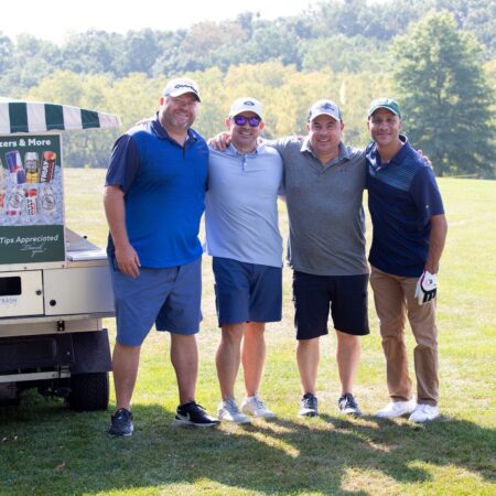 a group of men standing in front of a golf cart