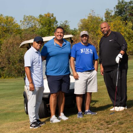 a group of men standing next to a golf cart