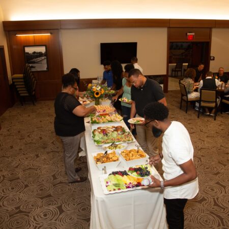 a group of people standing at a table with food on it