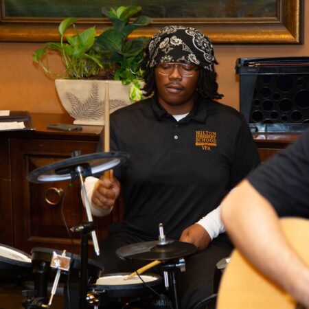 a person playing drums with another person in the background