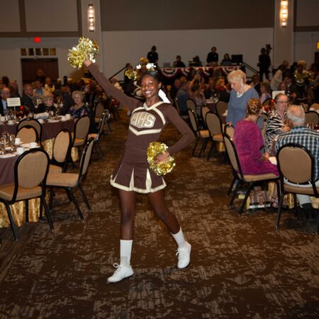 a cheerleader in a room with tables and chairs