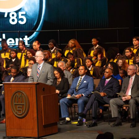 a person standing at a podium with a crowd of people
