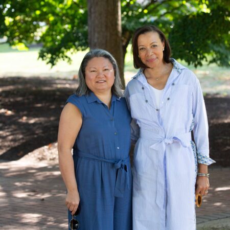 a couple of women standing under a tree