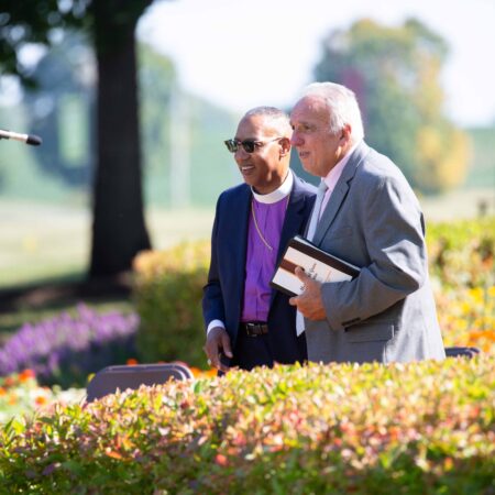 a person holding a book and another person standing in a garden