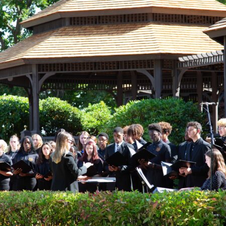 a group of people singing in front of a gazebo