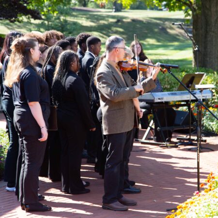 a group of people standing on a sidewalk playing a violin