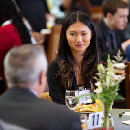 a person sitting at a table with a person in the background