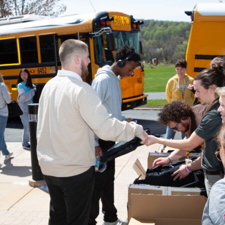 a person shaking hands with a person in front of a school bus
