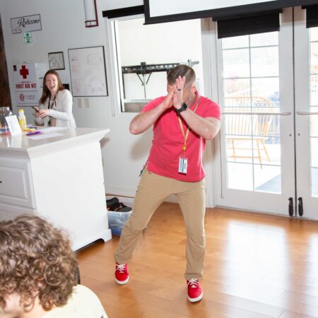 a person in red shirt and khaki pants standing in front of a group of people
