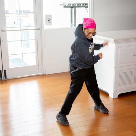 a person wearing a pink hat and sunglasses dancing in a room