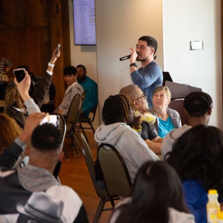 a person speaking into a microphone in front of a group of people