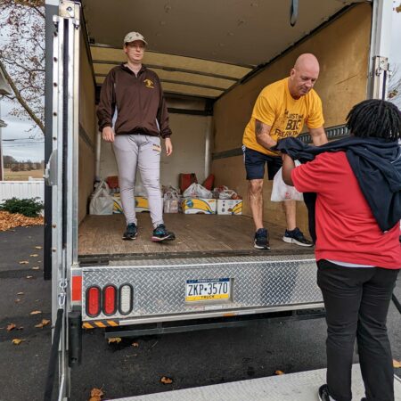 a couple of men standing in the back of a truck