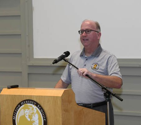 a person standing at a podium holding a microphone