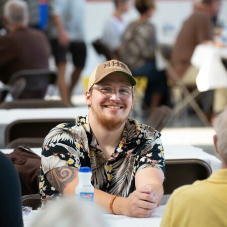 a person wearing a hat and smiling at a table