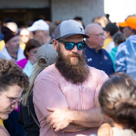 a person with a beard and cap standing in a crowd