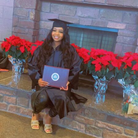 a person in a graduation gown holding a diploma