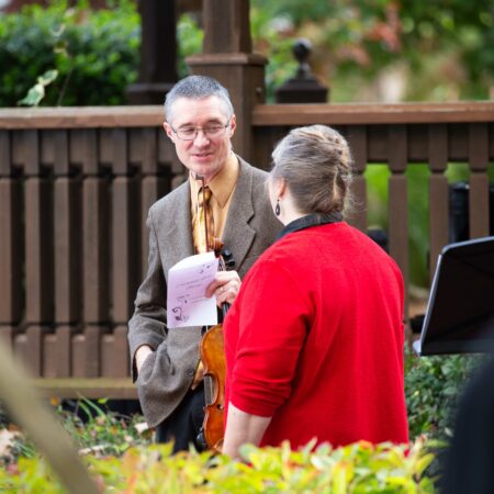 a person in a suit holding a piece of paper and a person in a red shirt